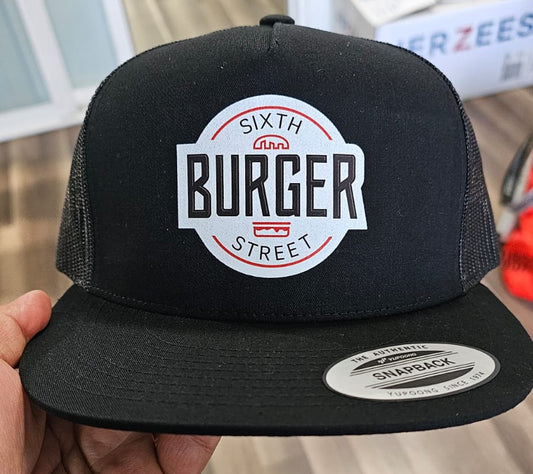 Black cap with 'Sixth Street Burger' logo held by a hand indoors.